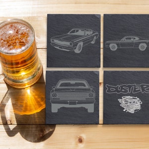 May include: Four black slate coasters with a gray outline of a classic car and the word "Duster" on one coaster.