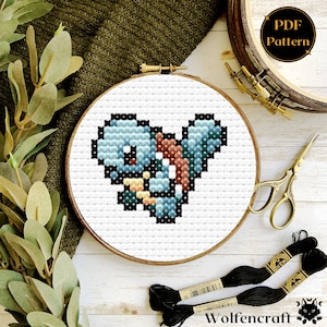 Könnte beinhalten: Ein Kreuzstichmuster eines blauen und braunen Pokemon-Charakters, Squirtle, in einem weißen Stickrahmen. Das Muster ist als PDF-Download verfügbar.