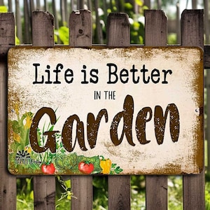 May include: A rustic metal sign with a distressed white background and brown text that reads "Life is Better in the Garden". The sign features a colorful illustration of a garden with vegetables and flowers.