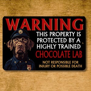 May include: Black metal sign with the text "WARNING" in red. It features a chocolate Labrador wearing a police uniform and the text "THIS PROPERTY IS PROTECTED BY A HIGHLY TRAINED CHOCOLATE LAB. NOT RESPONSIBLE FOR INJURY OR POSSIBLE DEATH."