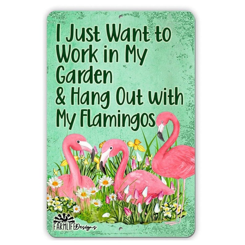 May include: A green metal sign with the text "I Just Want to Work in My Garden & Hang Out with My Flamingos". The sign features a pink flamingo design with flowers and greenery.
