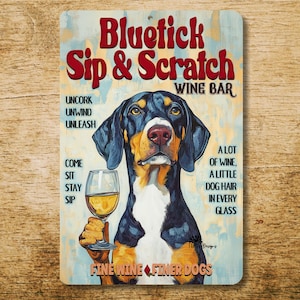 May include: A rectangular metal sign with a dog holding a wine glass. The sign reads "Bluetick Sip & Scratch Wine Bar" in red letters. Additional text includes "Fine Wine Finer Dogs."