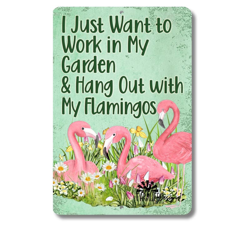 May include: A metal sign with a green background and white text that reads "I Just Want to Work in My Garden & Hang Out with My Flamingos". The sign features a watercolor illustration of three pink flamingos in a garden setting with flowers and greenery.