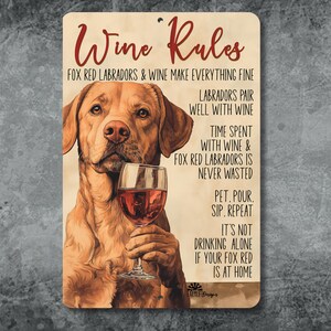 May include: A rectangular metal sign with rounded corners features a fox red Labrador holding a wine glass. The sign reads "Wine Rules" and includes text about wine and Labradors. The background has a vintage, distressed look.