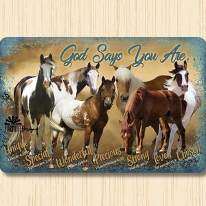 May include: A rustic metal sign with a distressed background featuring a group of six horses in various poses. The sign reads "God Says You Are" with a list of biblical verses and words describing the horses, including "Unique", "Special", "Wonderful", "Precious", "Strong", "Loved", and "Chosen".