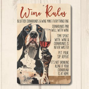 May include: A metal sign with a black and white illustration of a Bluetick Coonhound dog holding a glass of red wine. The sign has the text "Wine Rules" and a list of rules about drinking wine with Coonhounds.