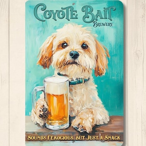 May include: A rectangular sign featuring a dog holding a beer mug. The sign reads "Coyote Bait Brewery" in teal lettering. The text "Sounds Ferocious, But Just a Snack" is at the bottom. The dog is light brown with a blue collar.