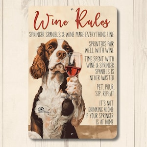 May include: A metal sign with a brown and white Springer Spaniel dog holding a glass of red wine. The sign says "Wine Rules" and has text about Springer Spaniels and wine.