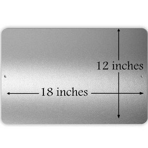 May include: A silver metal sign with black text that reads "18 inches" and "12 inches". The sign is rectangular and has rounded corners.