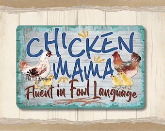 May include: A blue and yellow sign with the text "Chicken Mama Fluent in Fowl Language". The sign features a watercolor illustration of a mother hen and her chicks.