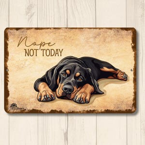May include: A rectangular metal sign with a distressed brown border and a tan background. The sign features a black and tan dog lying down with the text "Nope, NOT TODAY" in a handwritten font. The dog's eyes are open.