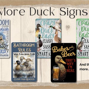 Puede incluir: Colecci&oacute;n de letreros con tem&aacute;tica de patos con varios dise&ntilde;os. Un letrero dice "Ba&ntilde;o" con ilustraciones de patos. Otros letreros presentan frases como "Crazy Duck Lady" y "Babes and Beer". Los letreros est&aacute;n sobre un fondo de madera.