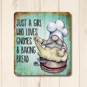 May include: A blue and green metal sign with a gnome wearing a white chef's hat and kneading dough in a bowl. The sign reads "Just a girl who loves gnomes & baking bread".