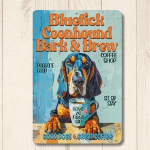 May include: A rectangular metal sign featuring a Bluetick Coonhound dog with a coffee cup. The sign reads "Bluetick Coonhound Bark & Brew Coffee Shop." Additional text includes "Doggone Good," "Love at First Sip," and "Good Dogs, Great Coffee."