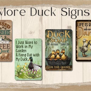 Puede incluir: Una colecci&oacute;n de letreros met&aacute;licos decorativos con dise&ntilde;os de patos. Los letreros presentan frases como "Coffee Duck obsessed" y "Life is better when you dance". Los letreros son de varios colores y estilos.