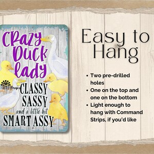 Puede incluir: Un letrero met&aacute;lico rectangular con un borde turquesa y un fondo de vetas de madera desgastada. El letrero presenta el texto "Crazy Duck Lady" en escritura morada, junto con ilustraciones de patos y patitos. Tambi&eacute;n se incluye el texto "Classy, Sassy, and a little bit Smart Assy".