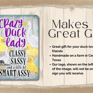 Puede incluir: Un letrero met&aacute;lico rectangular con un fondo azul claro y las palabras "Crazy Duck Lady" en escritura morada. El letrero presenta ilustraciones de patos y patitos, con las palabras "Classy, Sassy, and a little bit Smart Assy".