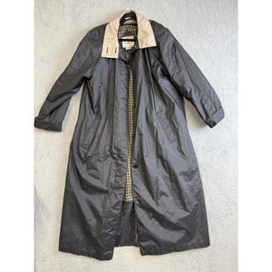 May include: A long, dark gray raincoat with a tan collar and a plaid lining. The coat has a button closure and long sleeves. The coat is made of a water-resistant material and is suitable for wet weather.