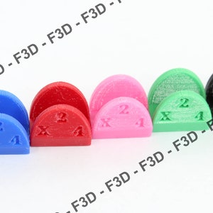 May include: Six half-circle shaped plastic pieces in different colors: orange, blue, red, pink, green, and black. Each piece has the numbers "1" and "2" and the letter "X" printed on it.