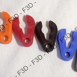May include: Seven plastic clips in various colors, including orange, red, black, blue, and gray. The clips are shaped like a V with a small hole in the center.