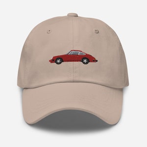 Può includere: Un cappello da baseball beige con un'auto rossa ricamata sul davanti.