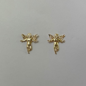 Pu&ograve; includere: Due statuette dorate di cherubini con le braccia tese e ali dettagliate. I cherubini sono rivolti in avanti, con una finitura liscia e lucida. Lo sfondo &egrave; di colore grigio chiaro uniforme. Queste statuette sono probabilmente oggetti decorativi.