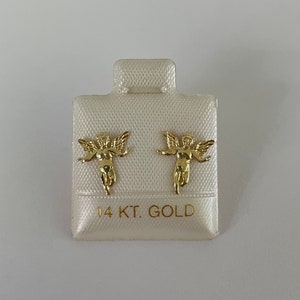 Pu&ograve; includere: Un paio di orecchini a lobo a forma di angelo color oro su un cartoncino bianco. Gli orecchini presentano un design dettagliato di cherubino con ali spiegate. Il cartoncino &egrave; etichettato "14 KT. GOLD".