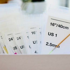 以下が含まれることがあります： さまざまなサイズで、米国サイズとミリメートルでラベル付けされた、40cmの編み針のセット。針は透明なプラスチック製の袋に入れられ、白い箱に整理されています。