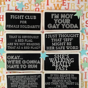 May include: A selection of black rectangular patches with white text, each displaying a different humorous quote. The patches are arranged on a colourful background with star-shaped decorations. The quotes include phrases like "Fight Club for Female Solidarity" and "I'm Not Your Gay Yoda."