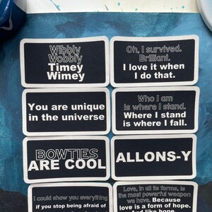 May include: Eight black rectangular patches with white text. The patches feature various quotes, including "Wibbly Wobbly Timey Wimey," "Bowties Are Cool," and "You are unique in the universe." The patches are likely for clothing or accessories.