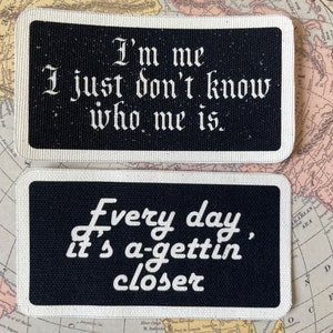 May include: Two rectangular patches with black backgrounds and white text. The top patch reads "I'm me, I just don't know who me is." The bottom patch says "Every day, it's a-gettin' closer."