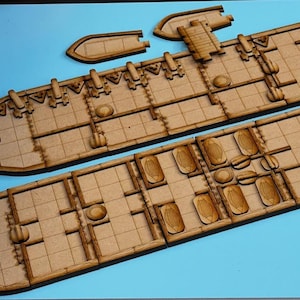 以下が含まれることがあります： 船の模型キット。木製で、船体、甲板、小型ボートなど複数の部品で構成されています。青い表面に部品が並べられています。