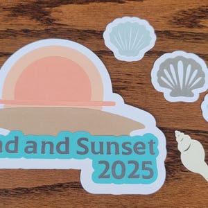 May include: A collection of beach-themed stickers. The main sticker features a sunset design with the text "Sand and Sunset 2025". Additional stickers include seashells in various colors. The stickers are on a wooden surface.