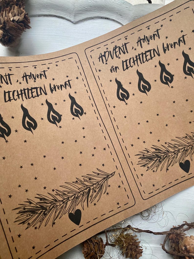 May include: Kraft paper sheets with the text "Advent, Advent ein Lichtlein brennt" in black script. The design includes black flame illustrations, stars, a sprig of pine, and a heart. The sheets are for a holiday theme.