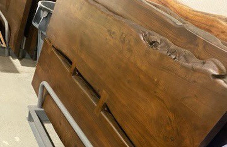 May include: A large, dark brown wooden headboard with a live edge and natural wood grain. The headboard has a unique, organic shape with a large knot in the wood.