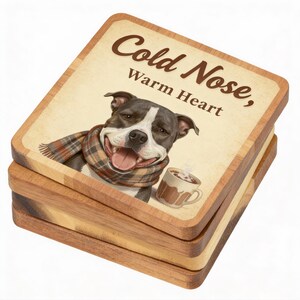 May include: Stack of four wooden coasters. The top coaster features a smiling dog wearing a scarf, with the text "Cold Nose, Warm Heart." A mug of hot chocolate is also depicted. The coasters have a light brown border and a medium brown wood grain.