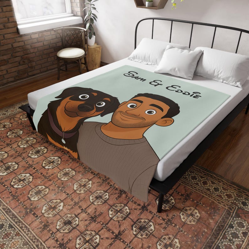May include: A light blue blanket with a cartoon illustration of a man and a dog, a Rottweiler. The blanket has the text "Sam & Eddie" in black script. The blanket is on a bed with white pillows.