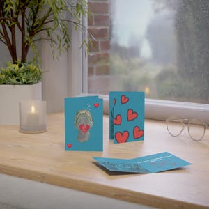 May include: A set of three Valentine's Day cards featuring a cartoon manatee holding a heart. The cards are blue with red hearts and the text "You are the Manatee for me".