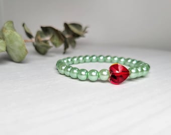 May include: A green beaded bracelet with a red heart-shaped crystal charm.