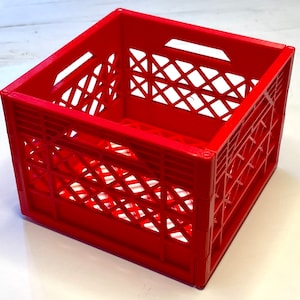 Puede incluir: Una caja de plástico roja con un patrón de rejilla. La caja está vacía y tiene una forma cuadrada.