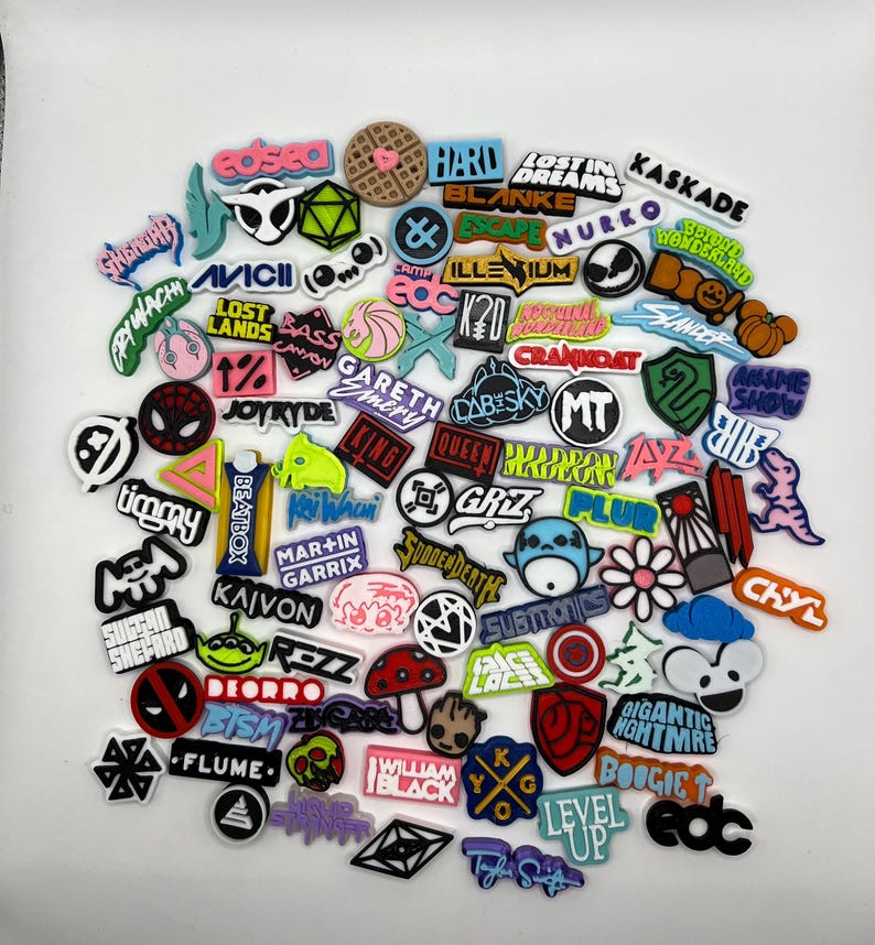 May include: A collection of colorful, round, and square stickers with various music artist names and logos. The stickers feature a variety of designs, including cartoon characters, geometric shapes, and text.