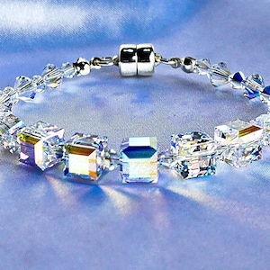 May include: A silver bracelet with a magnetic clasp and clear crystal beads. The beads are faceted and have a rainbow iridescent effect.