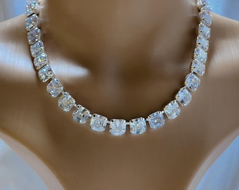 Puede incluir: Un collar de plata con piedras cuadradas transparentes. El collar está en un maniquí blanco.