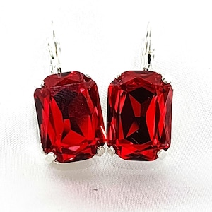 May include: A pair of silver earrings with large, red, faceted, rectangular gemstones.