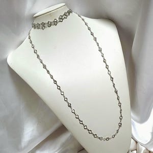80 Zoll lange Halskette aus Gold oder Silber (Rhodium). Kristallfassung. Zum Überziehen über den Kopf.
