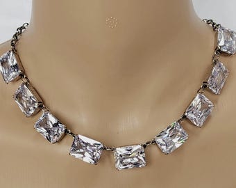 Può includere: Una collana a catena dorata con grandi pietre rettangolari trasparenti.