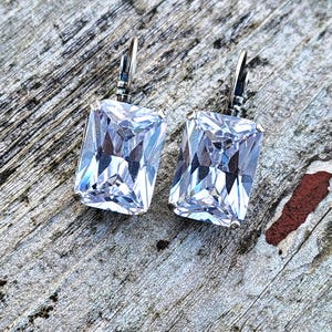 Op de afbeelding: Een paar zilveren oorbellen met grote, heldere, rechthoekige zirkonia-stenen.