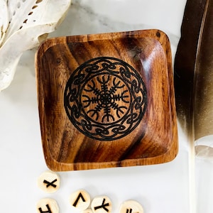 Può includere: Una ciotola di legno con una finitura marrone scuro e un design intagliato di un simbolo Vegvisir, un simbolo direzionale nordico, al centro. La ciotola è circondata da rune.