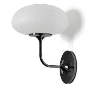 May include: A black wall sconce with a white glass shade. The sconce has a curved arm and a round base.