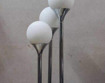 May include: A set of three modern floor lamps. Each lamp features a chrome-colored, slender pole topped with a white, spherical globe. The lamps are arranged in a row, creating a minimalist and stylish lighting fixture.